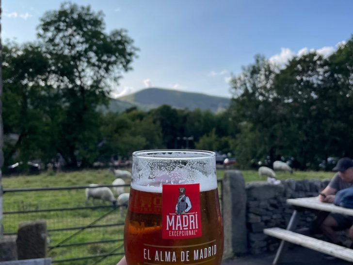 beer in hand with hills in background representing the best peak district pubs